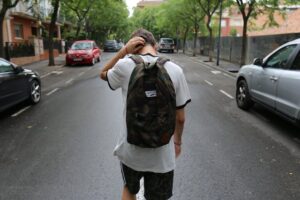 photo of a teenage boy wearing a backpack walking down a street